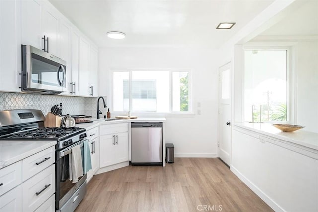 kitchen featuring sink, white cabinetry, tasteful backsplash, appliances with stainless steel finishes, and light hardwood / wood-style floors