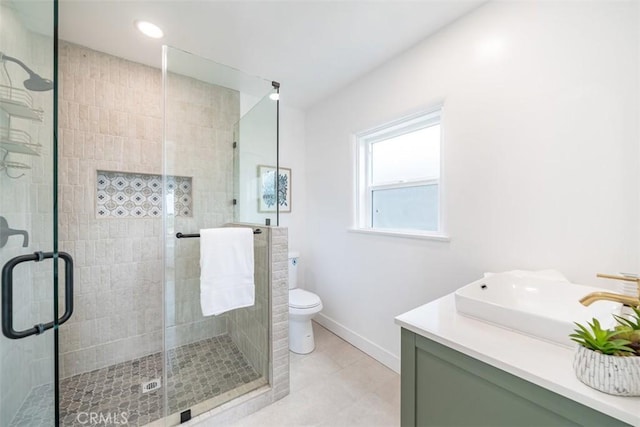 bathroom featuring toilet, tile patterned flooring, walk in shower, and vanity