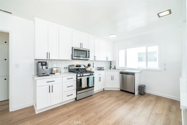 kitchen featuring backsplash, sink, white cabinetry, light wood-type flooring, and appliances with stainless steel finishes