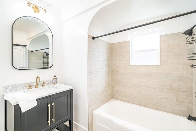 bathroom featuring tiled shower / bath, vanity, and ornamental molding