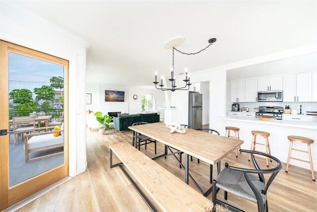 dining area with a chandelier, crown molding, and light hardwood / wood-style floors