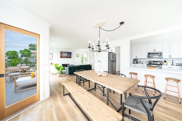 dining area featuring a healthy amount of sunlight, an inviting chandelier, and light hardwood / wood-style flooring