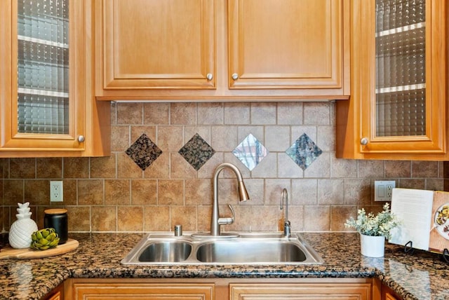 kitchen featuring decorative backsplash, dark stone countertops, and sink