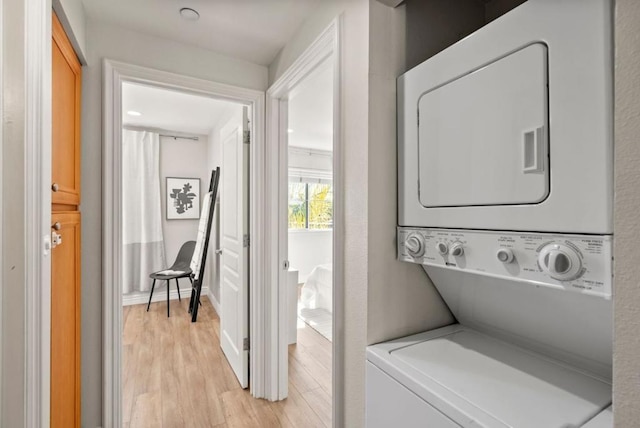 laundry room featuring light wood-type flooring and stacked washer / drying machine