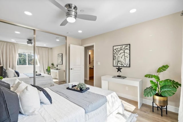 bedroom with light wood-type flooring, ceiling fan, and a closet