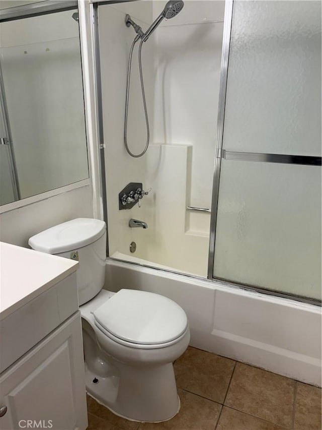 full bathroom featuring combined bath / shower with glass door, vanity, tile patterned floors, and toilet