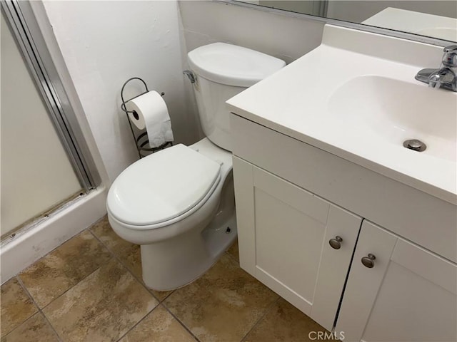 bathroom featuring toilet, a shower with shower door, and vanity