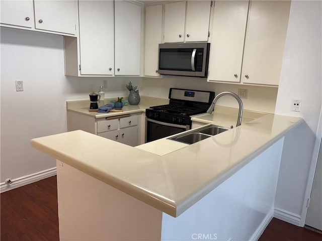 kitchen with dark wood-type flooring, appliances with stainless steel finishes, white cabinets, and sink