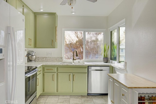 kitchen featuring range, dishwasher, green cabinetry, white refrigerator with ice dispenser, and sink