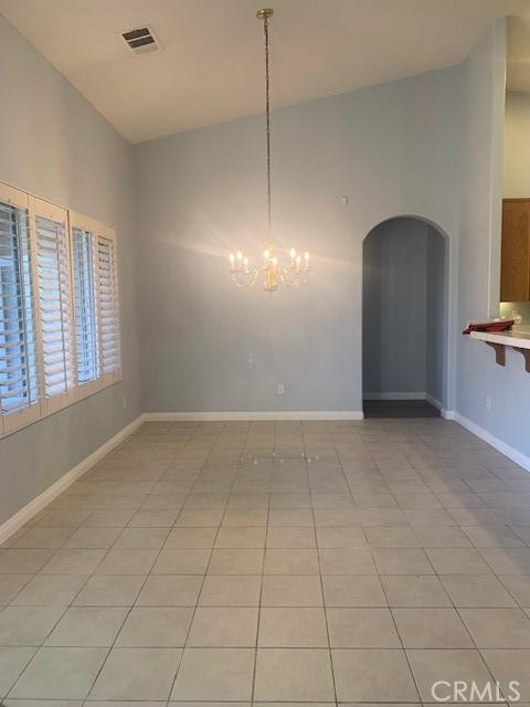 unfurnished dining area featuring an inviting chandelier and light tile patterned floors