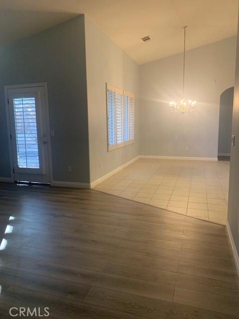 empty room featuring vaulted ceiling, a chandelier, and hardwood / wood-style floors