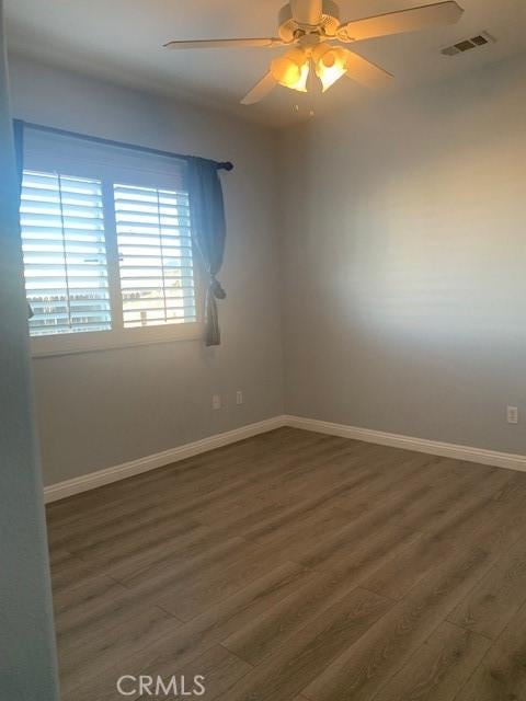 empty room with ceiling fan and dark hardwood / wood-style flooring