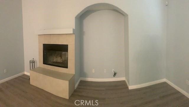 unfurnished living room with dark hardwood / wood-style flooring and a tile fireplace