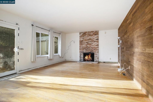 unfurnished living room featuring a brick fireplace and hardwood / wood-style flooring