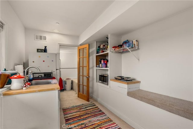 kitchen with white fridge, stainless steel microwave, light colored carpet, french doors, and sink