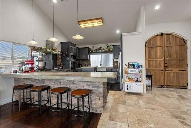 kitchen featuring kitchen peninsula, gray cabinets, stainless steel appliances, lofted ceiling, and hanging light fixtures