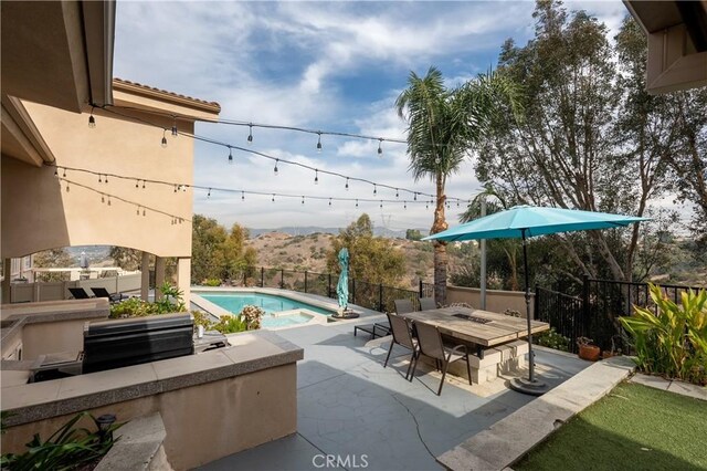 view of patio with a fenced in pool, an outdoor kitchen, and a mountain view