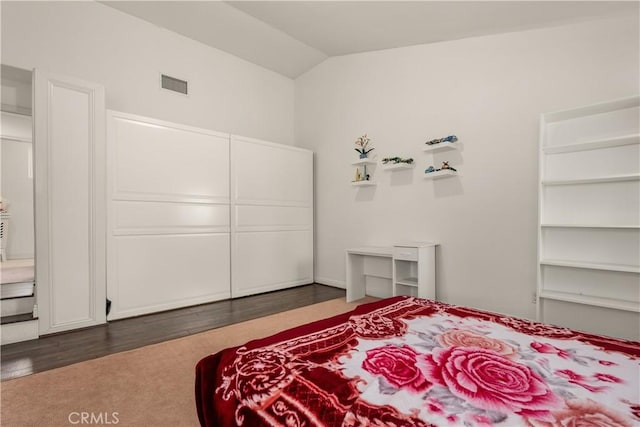 bedroom with vaulted ceiling and dark wood-type flooring