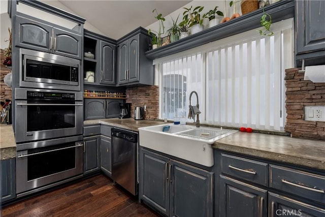 kitchen featuring appliances with stainless steel finishes, lofted ceiling, sink, backsplash, and dark hardwood / wood-style floors