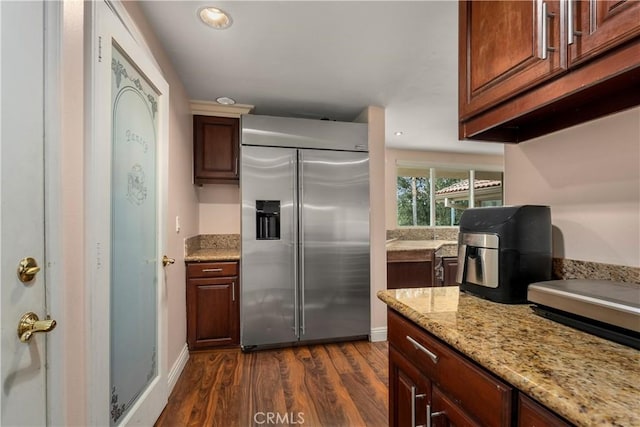 kitchen with light stone countertops, stainless steel built in fridge, and dark hardwood / wood-style floors