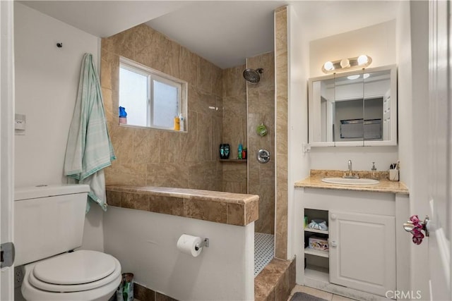 bathroom with vanity, toilet, tile patterned flooring, and tiled shower