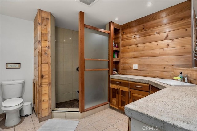 bathroom featuring toilet, tile patterned flooring, a tile shower, and vanity