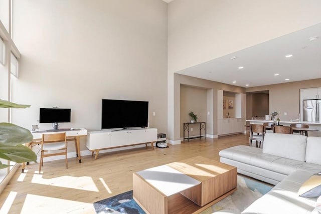 living room with a towering ceiling and light wood-type flooring