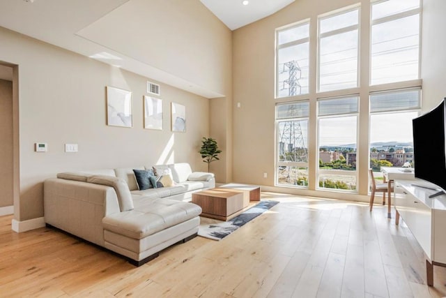 living room with light hardwood / wood-style flooring and a high ceiling