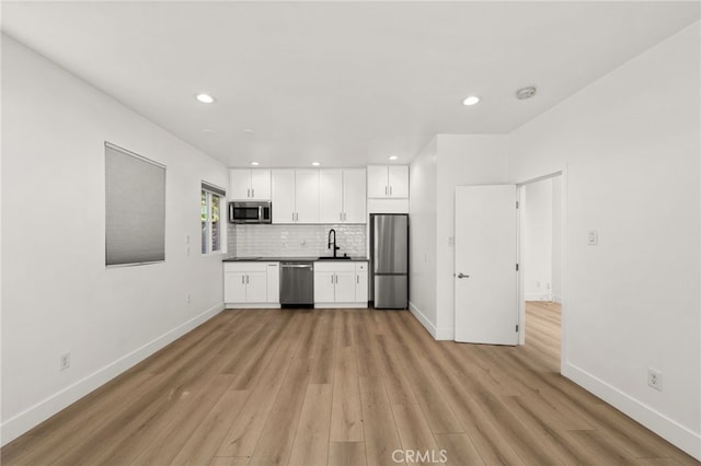 kitchen featuring white cabinets, appliances with stainless steel finishes, sink, backsplash, and light hardwood / wood-style flooring