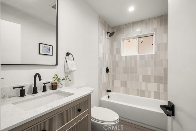 full bathroom with wood-type flooring, toilet, vanity, and tiled shower / bath