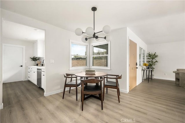 dining area featuring sink, wood-type flooring, and a notable chandelier