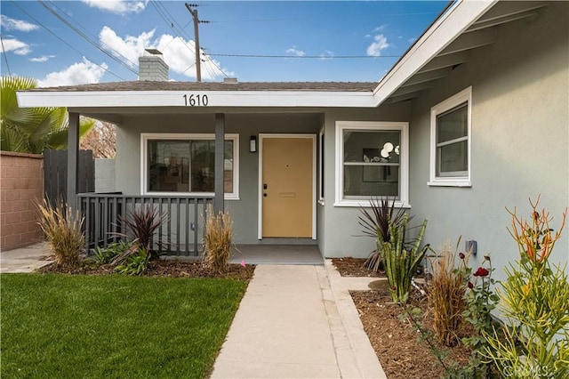 doorway to property with covered porch and a yard