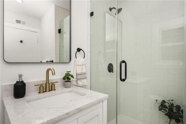 bathroom featuring a shower with door and vanity