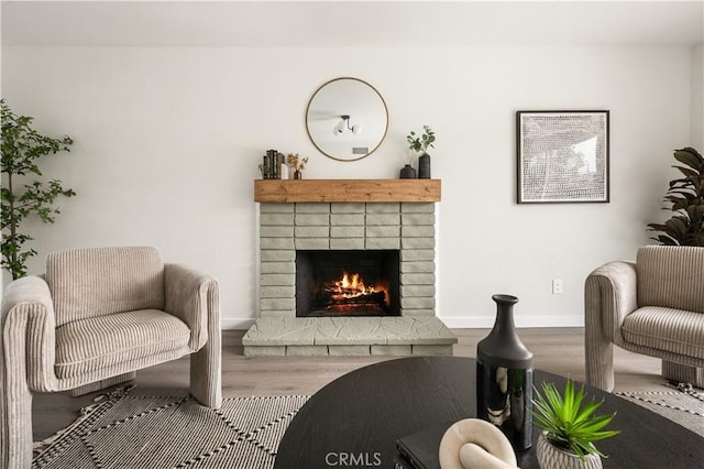 living room with a brick fireplace and hardwood / wood-style floors