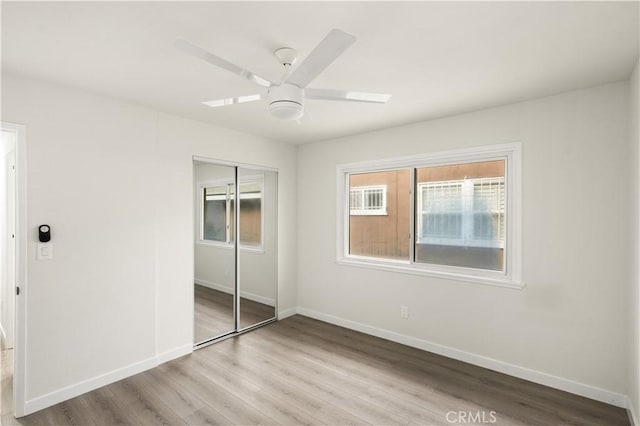 unfurnished bedroom featuring a closet, light hardwood / wood-style floors, and ceiling fan