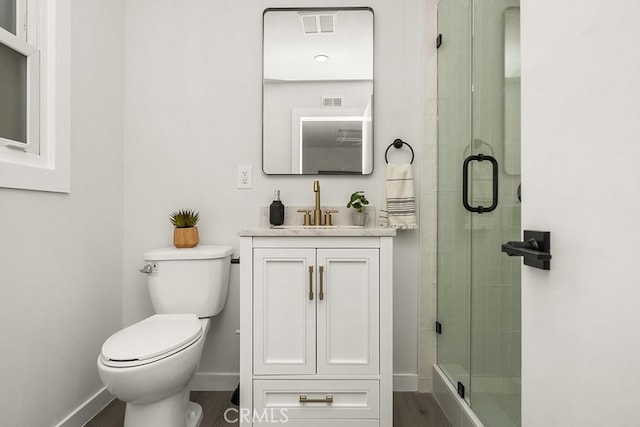 bathroom featuring toilet, hardwood / wood-style flooring, a shower with door, and vanity