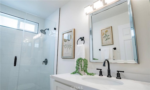 bathroom with a shower with shower door and vanity