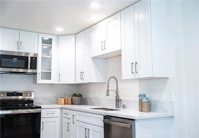 kitchen with appliances with stainless steel finishes, white cabinetry, and sink