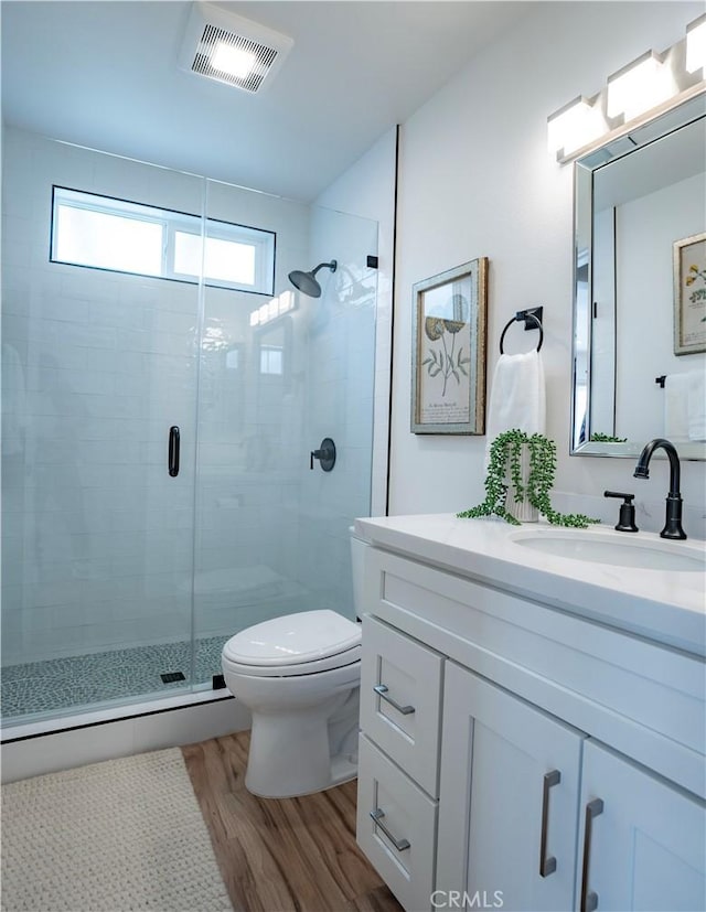 bathroom with toilet, vanity, wood-type flooring, and an enclosed shower