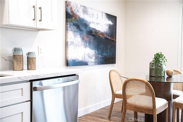 interior space with white cabinetry, stainless steel dishwasher, light hardwood / wood-style flooring, and light stone counters