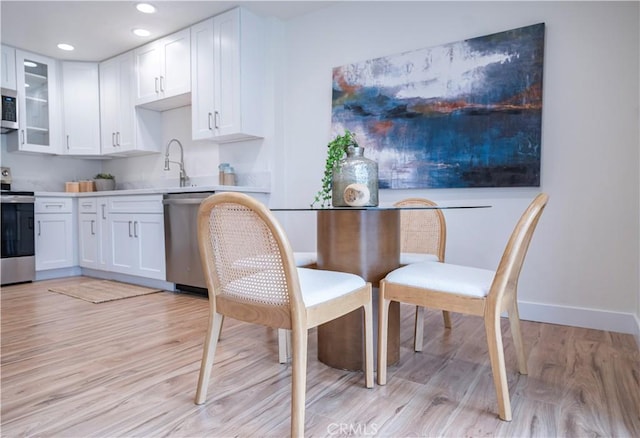 kitchen with stainless steel appliances, light hardwood / wood-style flooring, and white cabinets