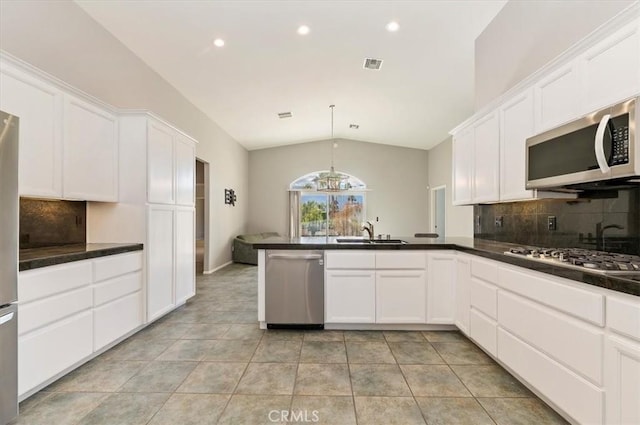 kitchen with vaulted ceiling, stainless steel appliances, dark countertops, and white cabinets