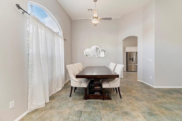 dining area featuring baseboards, arched walkways, and ceiling fan