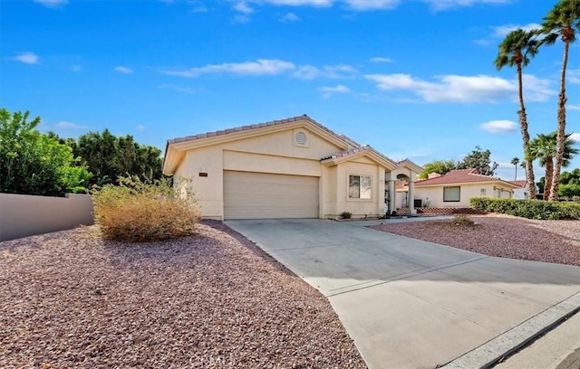 mediterranean / spanish-style home with a garage, concrete driveway, fence, and stucco siding