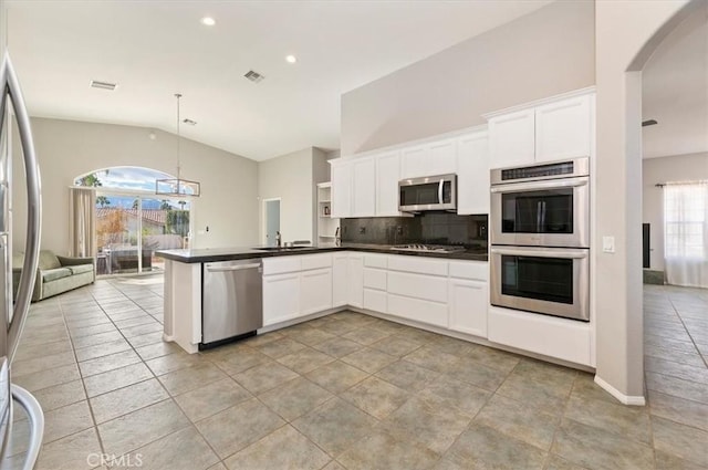 kitchen with decorative light fixtures, stainless steel appliances, dark countertops, open floor plan, and white cabinetry