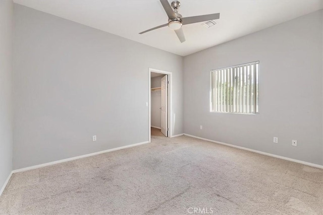 spare room featuring a ceiling fan, light colored carpet, visible vents, and baseboards