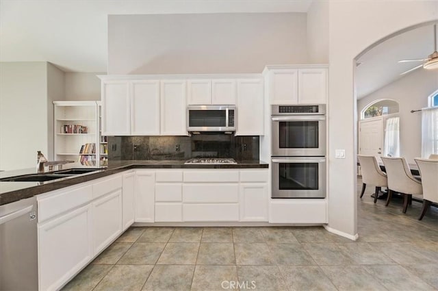 kitchen with appliances with stainless steel finishes, dark countertops, a sink, and white cabinets