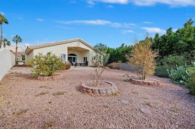 rear view of house featuring fence and stucco siding