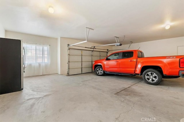 garage with a garage door opener and freestanding refrigerator