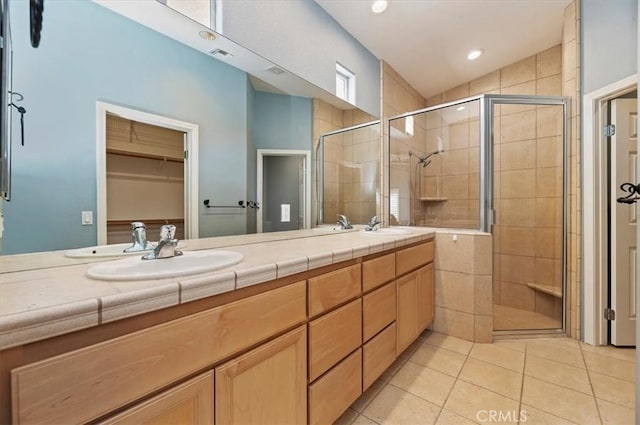 bathroom featuring double vanity, visible vents, a stall shower, a sink, and tile patterned flooring